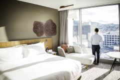 Guest standing at the window of a city-view room, Crowne Plaza Hobart.