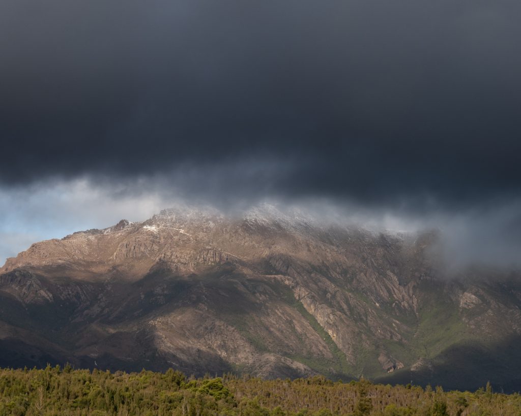 Stormy clouds gathering over jagged Tasmanian mountain peak
